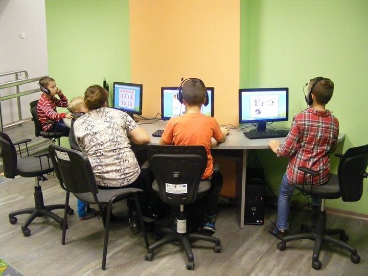Przy czterech stanowiskach komputerowych siedzą dzieci biorą udział w interaktywnym kursie języka angielskiego dla dzieci do lat 12.