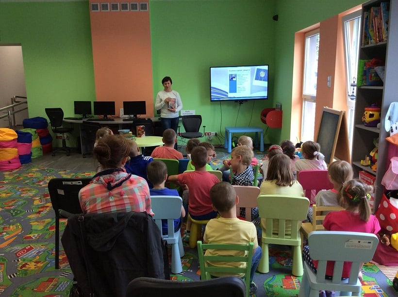 Na krzesełkach siedzą dzieci ze SP3 bibliotekarka Ania Wiśniewska prowadzi lekcję na temat powstawania i różnorodności książek.