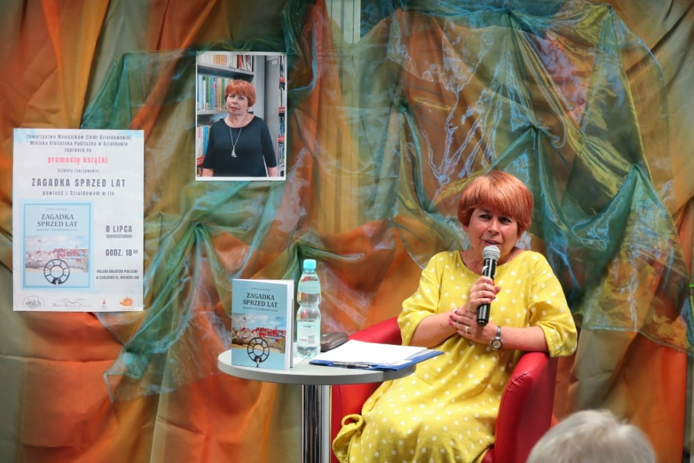 Na czerwonym fotelu siedzi autorka książki ''Zagadka sprzed lat'' Elżbieta Zakrzewska.