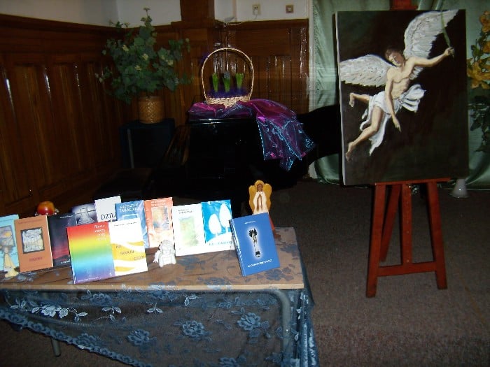 Wnętrze szkoły muzycznej, na stoliku leżą książki i obok na sztaludze obraz anioła.