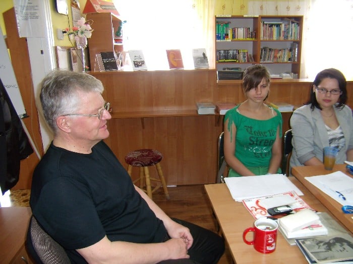 Wnętrze biblioteki. Przy stoliku Marek Barański - dziennikarz i redaktor Gazety Olsztyńskiej, a także autor czterech tomików poezji przeprowadza warsztaty z dziennikarstwa dla młodzieży.