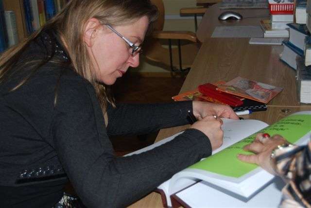 Przy stoliku podpisuje książkę dziennikarka prasowa i telewizyjna, autorka powieści dla młodzieży Karolina Piekarska.