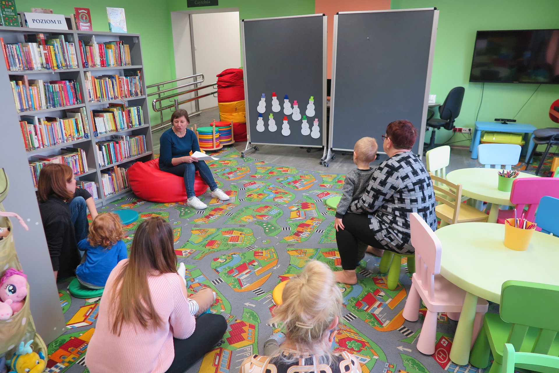 Wnętrze biblioteki, (Klub Malucha) bibliotekarka Ania Wiśniewska czyta dzieciom wierszyk o dziesięciu bałwankach.
