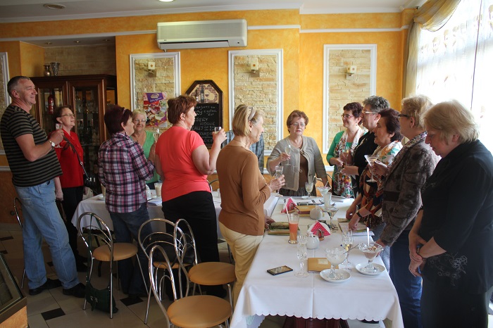 Wnętrze restauracji, przy stolikach siedzą członkowie DKK UTW wspólnie omawiają  książkę Krystyny Sztramskiej "Takie zwykłe szczęście", na stole kawa i desery.