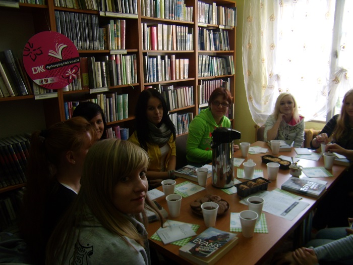 Wnętrze biblioteki. Przy stoliku siedzą członkinie DKK ZS Malinowo wspólnie omawiają książkę  R.P. Evansa "Papierowe marzenia".