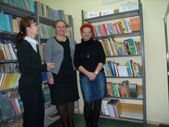 Wnętrze biblioteki, między regałami z książkami stoi dyrektor MBP Justyna Lytvyn i dwie bibliotekarki.
