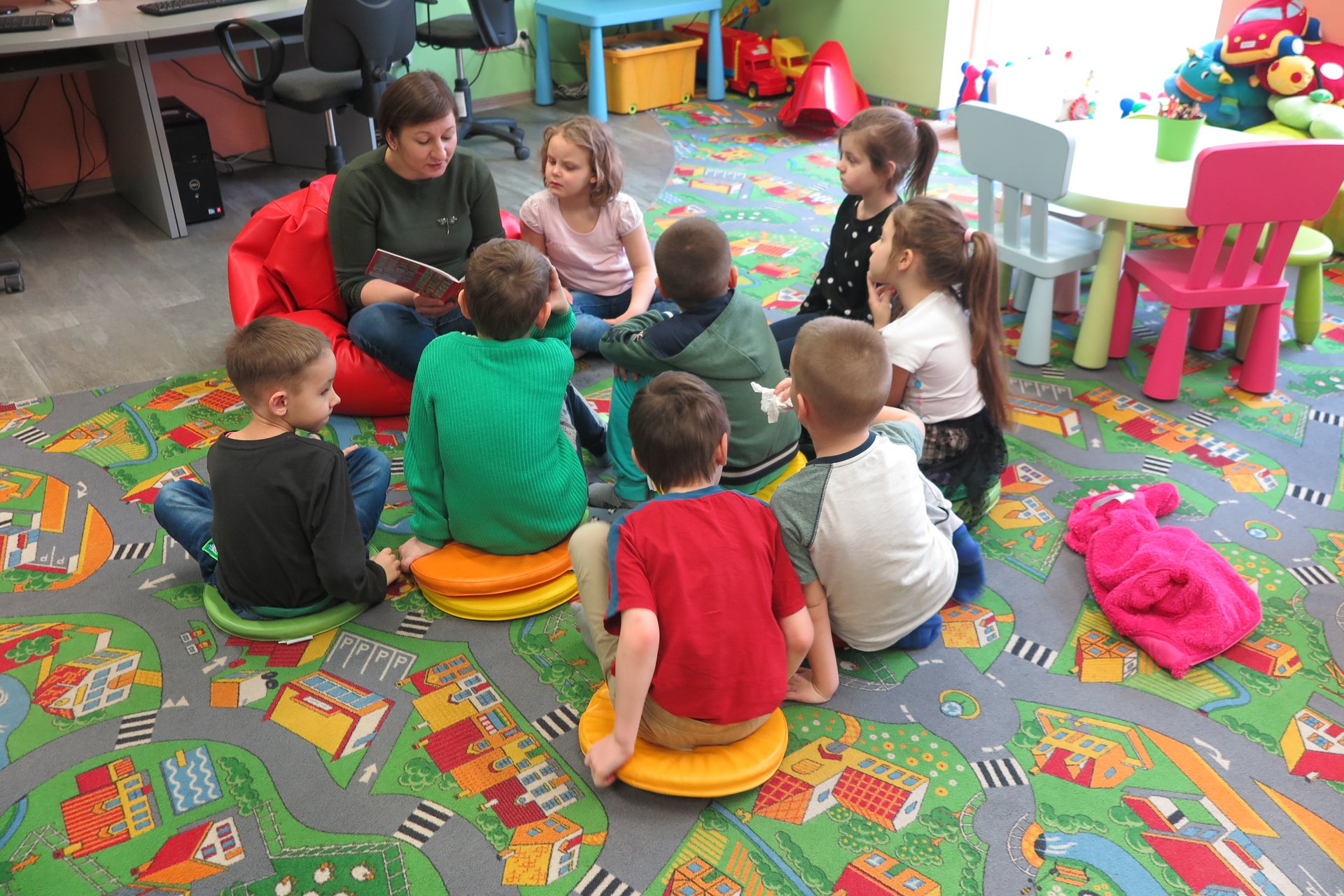 Wnętrze biblioteki (Klub Malucha)  bibliotekarka Ania Wiśniewska czyta dzieciom opowiadanie ''Franklin i walentynki'' ośmioro dzieci z przedszkola nr 4 w Działdowie uważnie słucha.  