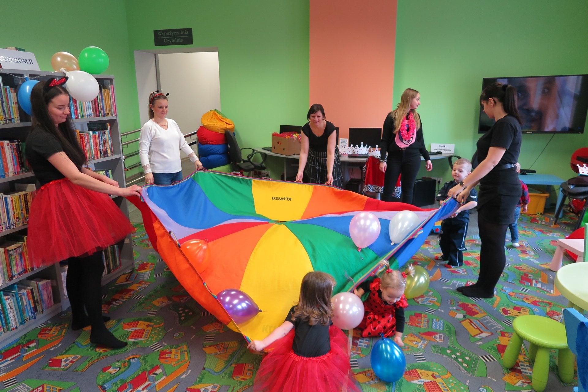Wnętrze biblioteki (Klub Malucha) Pierwszy bal  karnawałowy maluchów! Bibliotekarka Ania Wiśniewska bawi się z dziećmi towarzyszą im opiekunowie. 