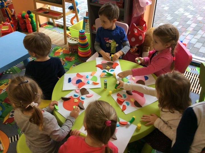Przy okrągłym stoliku siedzą cztery dziewczynki i dwóch chłopców wspólnie wykonują prace plastyczne,kolorowe sowy.