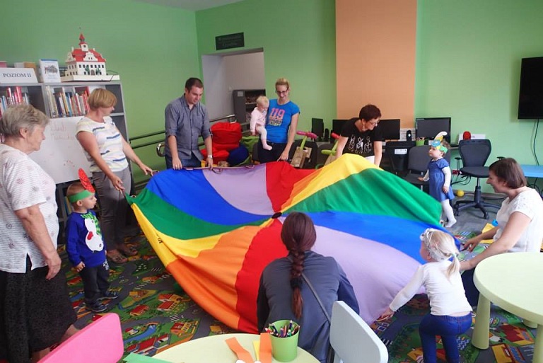 Zabawa z kolorową chustą z uczestnikami Klubu Malucha w oddziale dla dzieci.