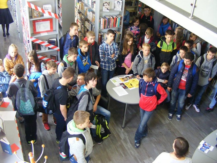 Wnętrze biblioteki. Grupa gimnazjalistów z Gródek zwiedza oddział dla dorosłych.