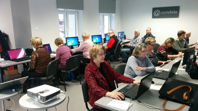 12 uczestników kursu komputerowego przy stanowiskach w bibliotece w dziale mediateka.