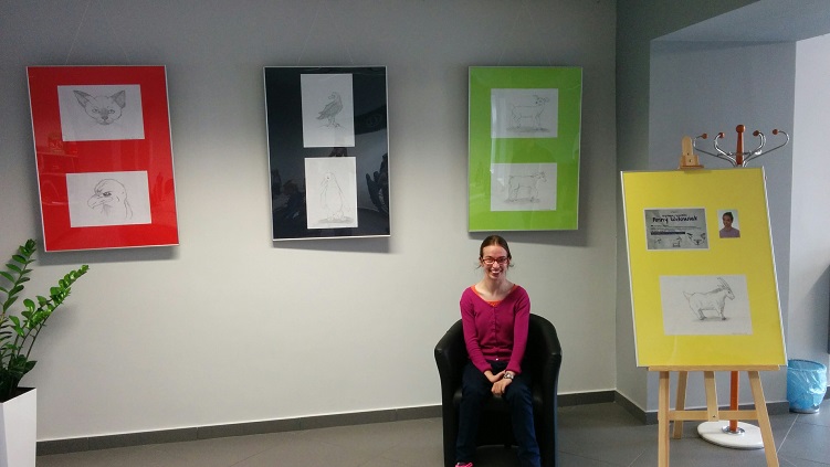 Na ścianie wisi wystawa rysunków, na fotelu siedzi ich autorka Anna Wdowiak.