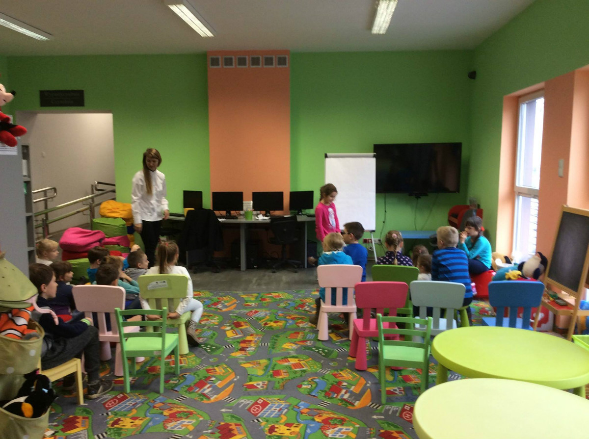 Wnętrze biblioteki. Grupa dzieci ze świetlicy  Szkoły Podstawowej nr 3 bierze udział w zajęciach edukacyjnych. 