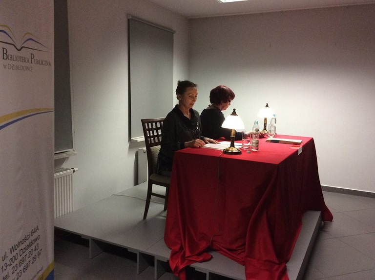 Na podeście przy czerwonym stoliku siedzą panie Irena Telesz-Burczyk i Joanna Fertacz.