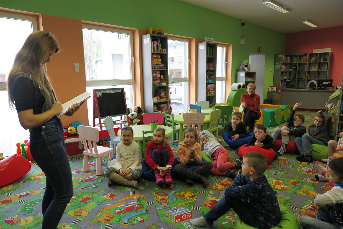 Wnętrze biblioteki. Dzieci ze świetlicy ze SP nr 3 biorą udział w turnieju "Jeden z piętnastu", zajęcia prowadzi bibliotekarka Aleksandra Cybulska.