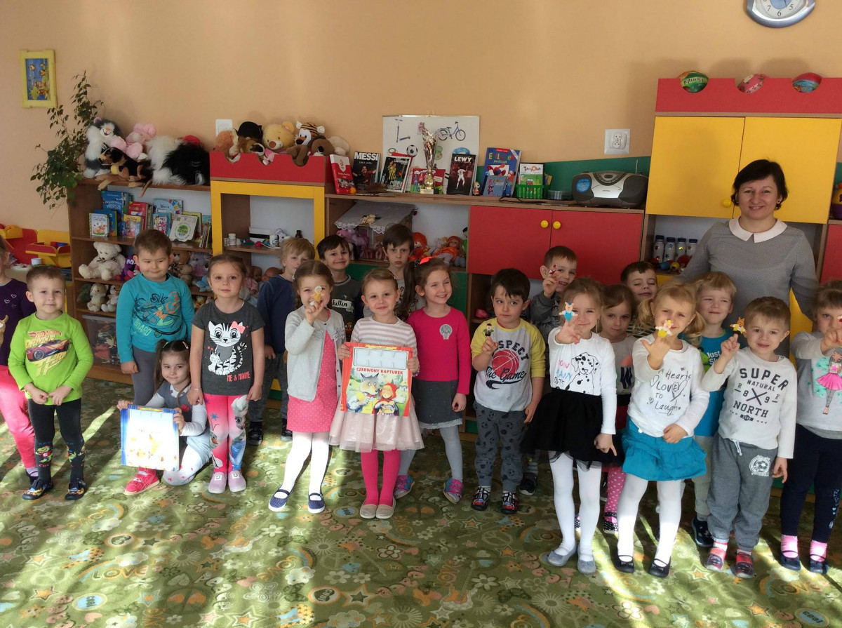 Wnętrze Przedszkola nr 5, grupa dzieci stoi razem z bibliotekarką Anią Wiśniewską. 