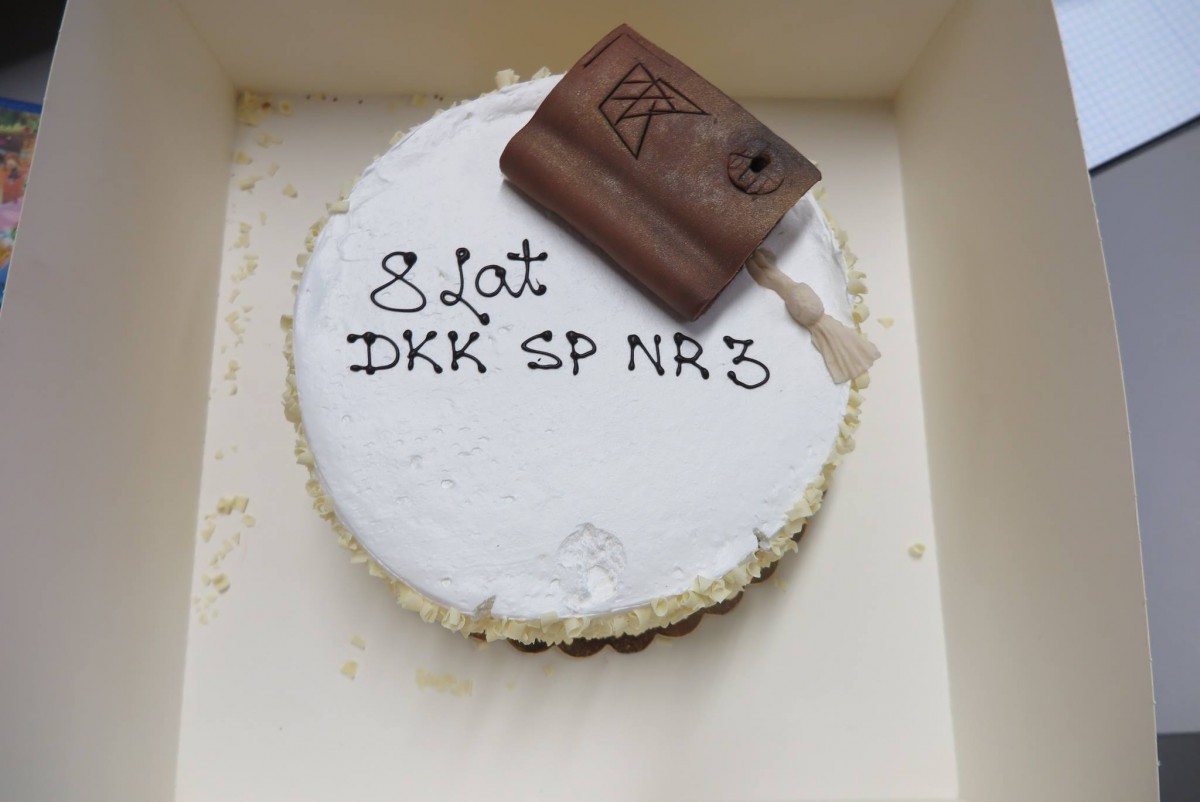 Tort z czekoladową książką i napisem 8 lat DKK SP nr 3. 