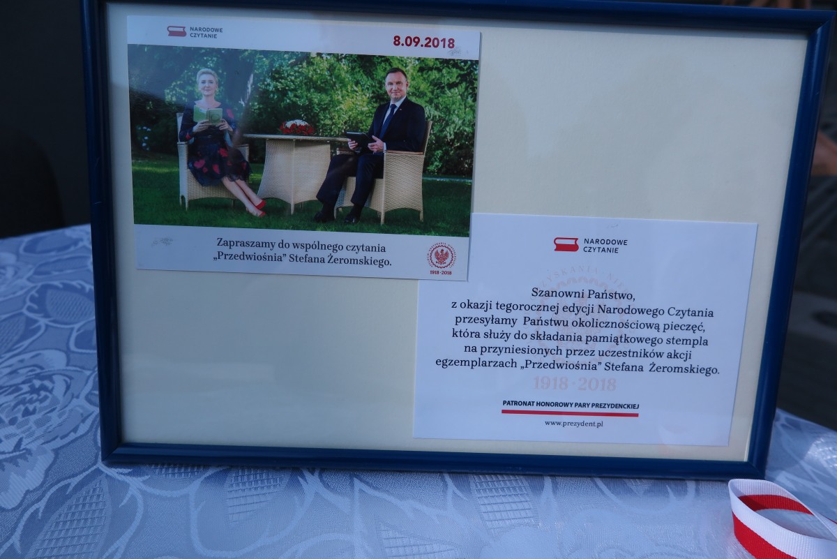 Na stoliku ramka ze zdjęciem pary prezydenckiej z 8.09.2018r.  z narodowego  czytania powieści ,,Przedwiośnia' Stefana Żeromskiego. 