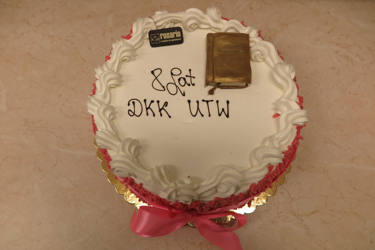 Tort z napisem 8 lat DKK UTW  ze złotą książeczką. 