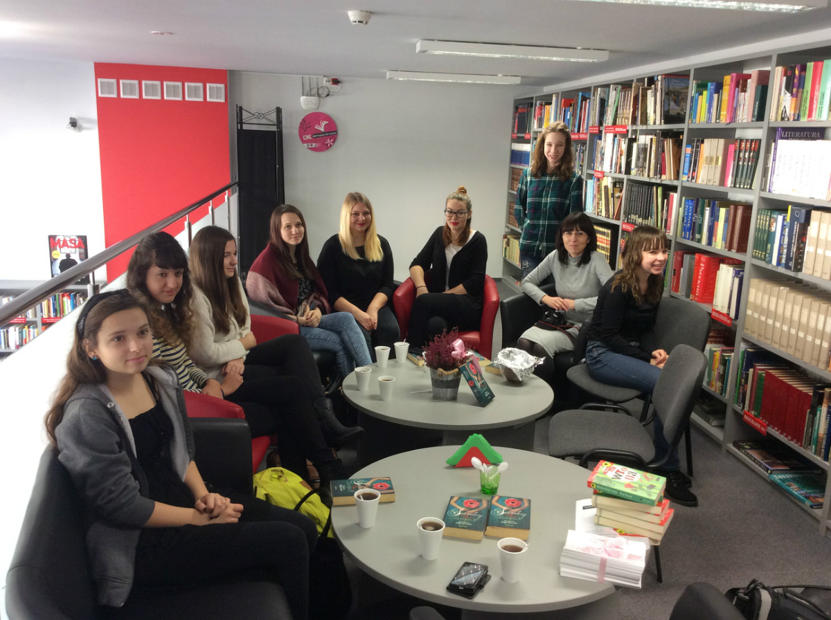 Wnętrze biblioteki. Przy stolikach grupa młodzieży z DKK ZS Malinowo wspólnie omawiają książkę  Vanessy Diffenbaugh "Sekretny język kwiatów".