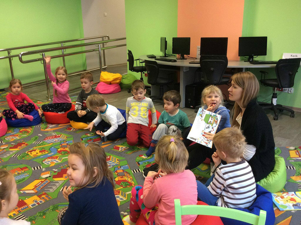 Wnętrze biblioteki. W kole siedzą dzieci z Przedszkola nr 3, bibliotekarka Aleksandra Cybulska czyta  opowiadanie  "Zima" Małgorzaty Strzałkowskiej.