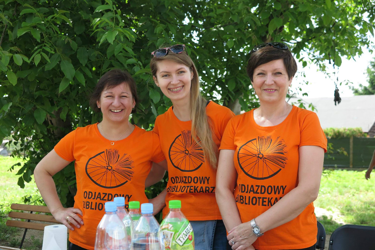 Na placu przed MBP trzy bibliotekarki Ania Wiśniewska, Aleksandra Cybulska i Mariola Wilkowska w pomarańczowych koszulkach ''Odjazdowy Bibliotekarz''.