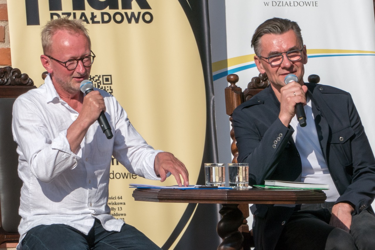 Przy stoliku siedzą aktor Andrzej Mastalerz oraz poeta Wojciech Kassa. 