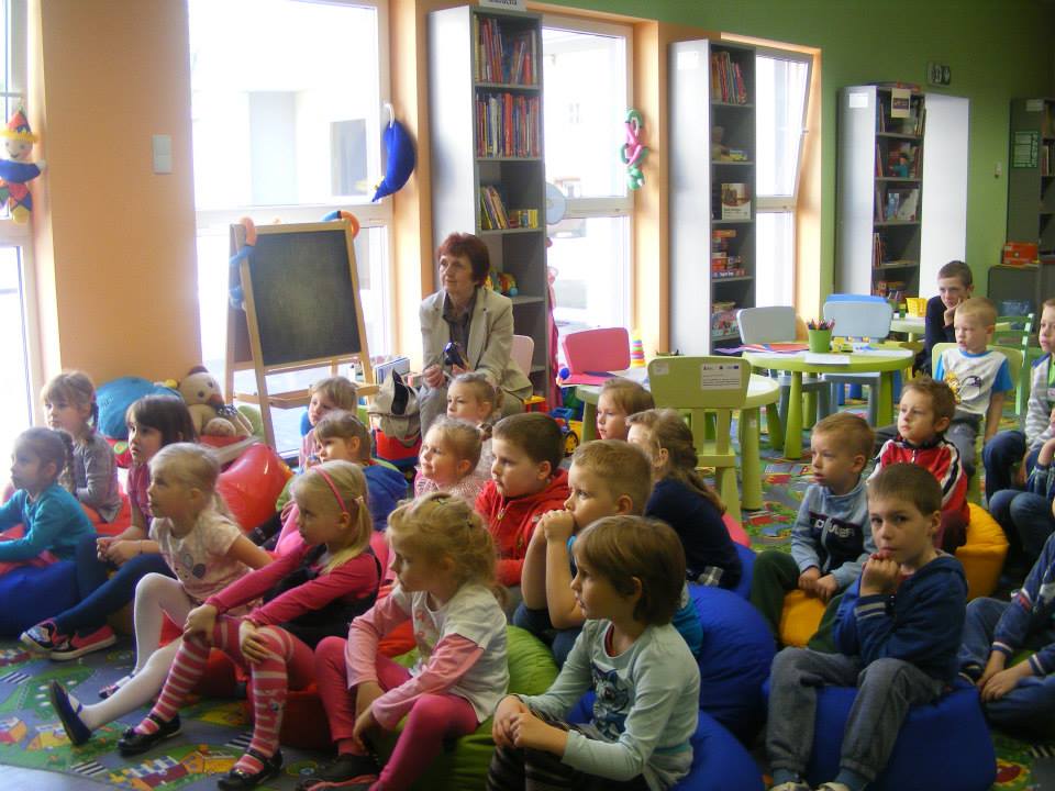 Wnętrze biblioteki. Grupa dzieci z opiekunkami bierze udział w lekcji bibliotecznej na temat wody.