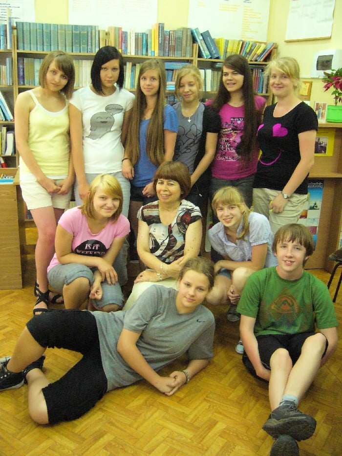 Wnętrze biblioteki, grupa dzieci z bibliotekarką Elżbietą Zakrzewską.