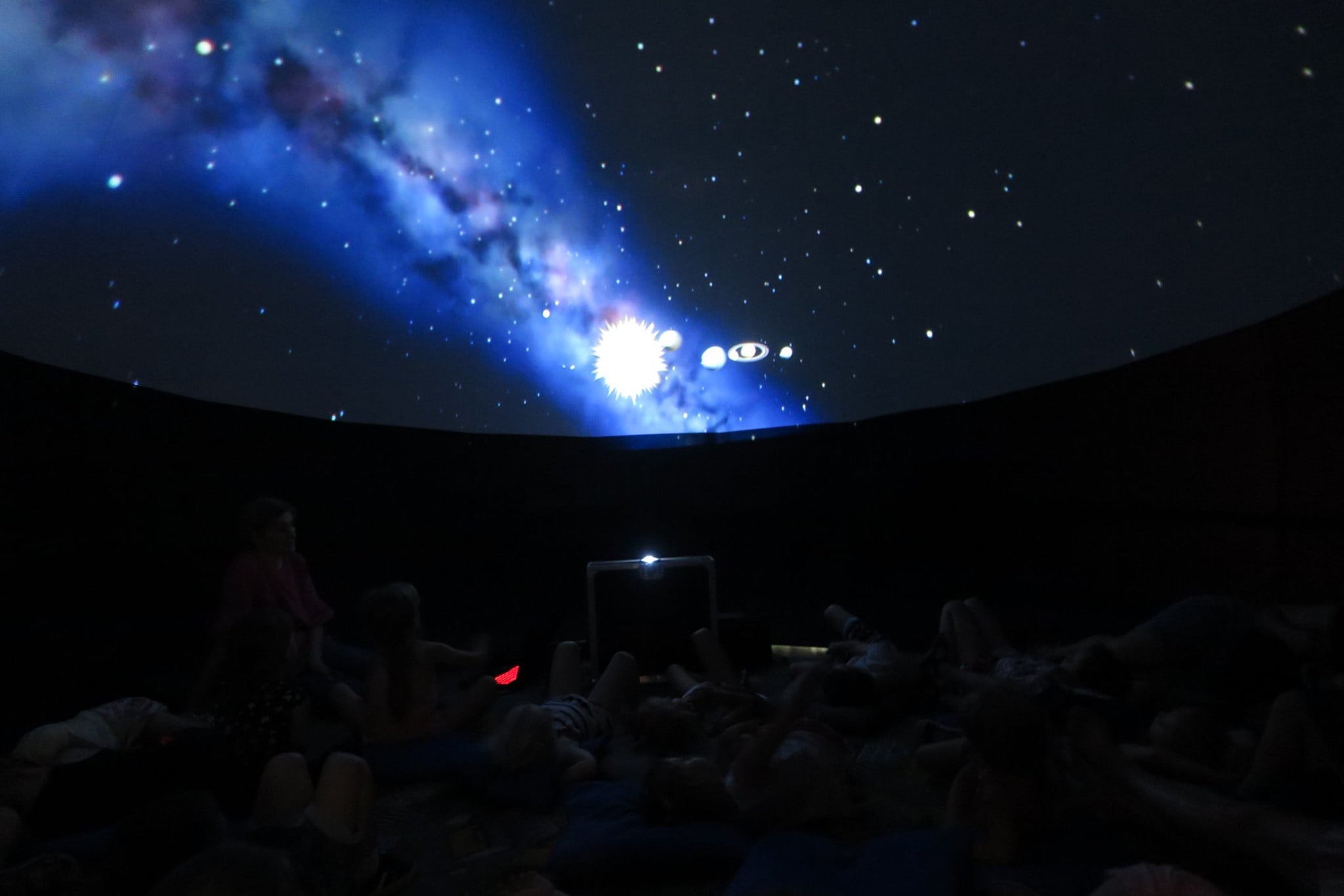 W mobilnym planetarium dzieci oglądają seans filmowy o historii lotów kosmicznych. 