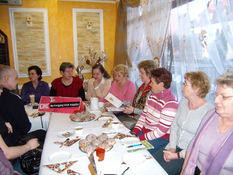 Wnętrze restauracji, Przy stoliku z pączkami i kawą siedzą członkowie DKK UTW wspólnie dyskutują o książce Glorii Goldreich "Kolacja z Anną Kareniną".