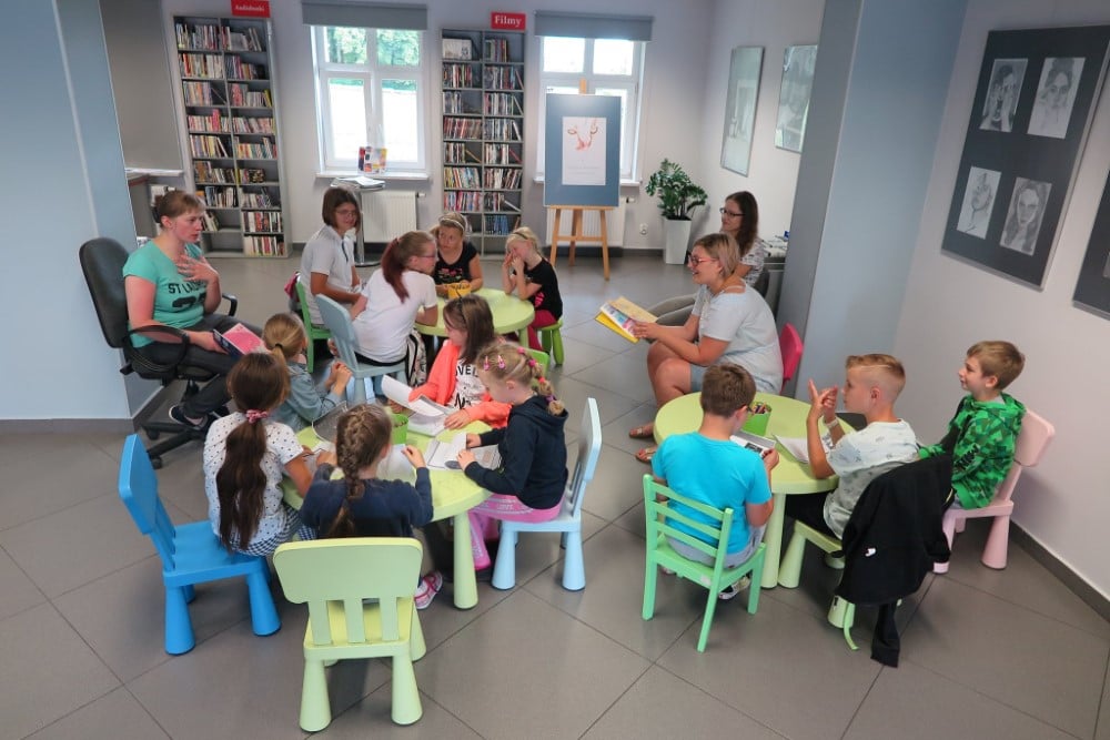 Wnętrze biblioteki. W pierwszym tygodniu wakacji dzieci robią prace plastyczne. Zajęcia prowadzi bibliotekarka Małgorzata Trąmpczyńska. 