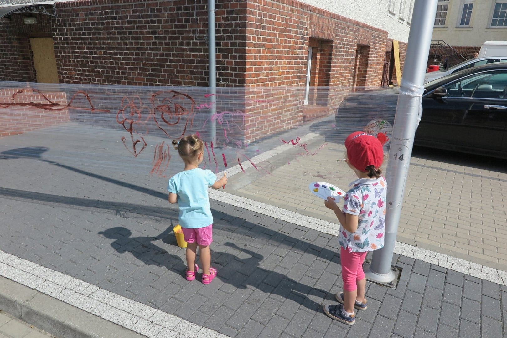 Na placu MBP dwie dziewczynki malują farbkami na folii. 