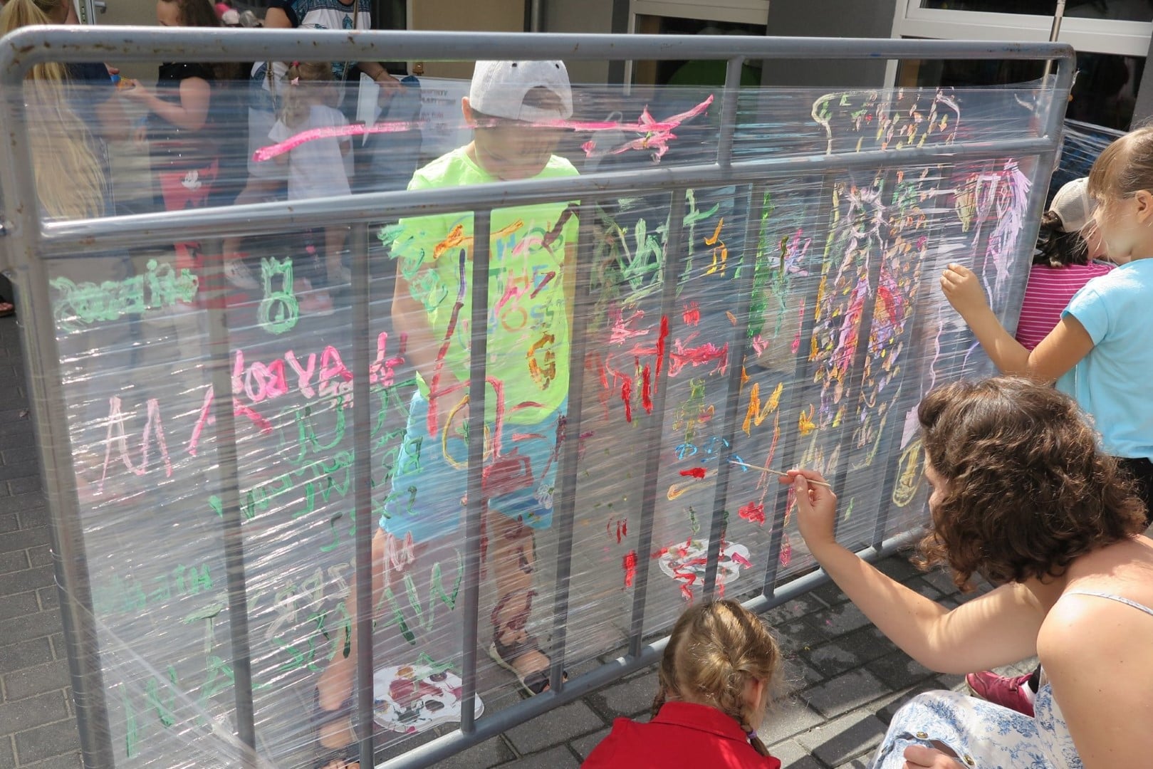Na placu MBP dzieci malują farbkami na folii. 