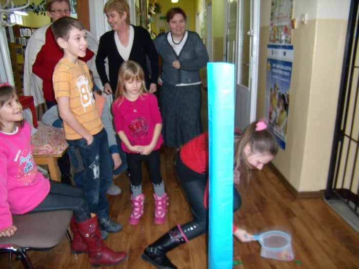 Wnętrze biblioteki, grupa dzieci gra w gry zręcznościowe.