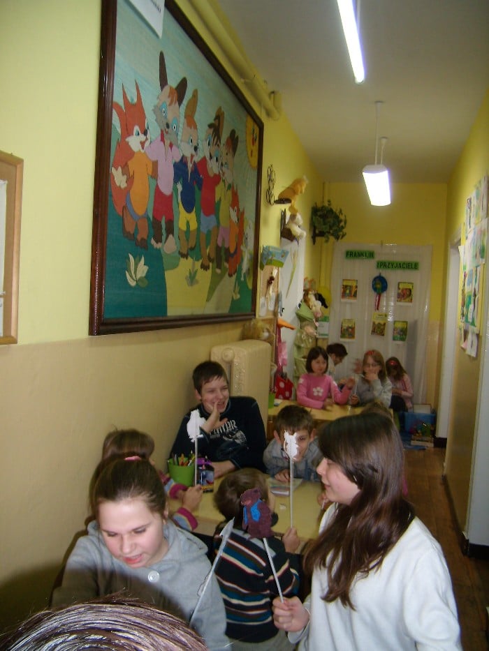 Przy stolikach grupa dzieci podczas zajęć w bibliotece.