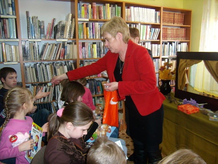 Bibliotekarka Marzena Pawłowska rozdaje dzieciom upominki.