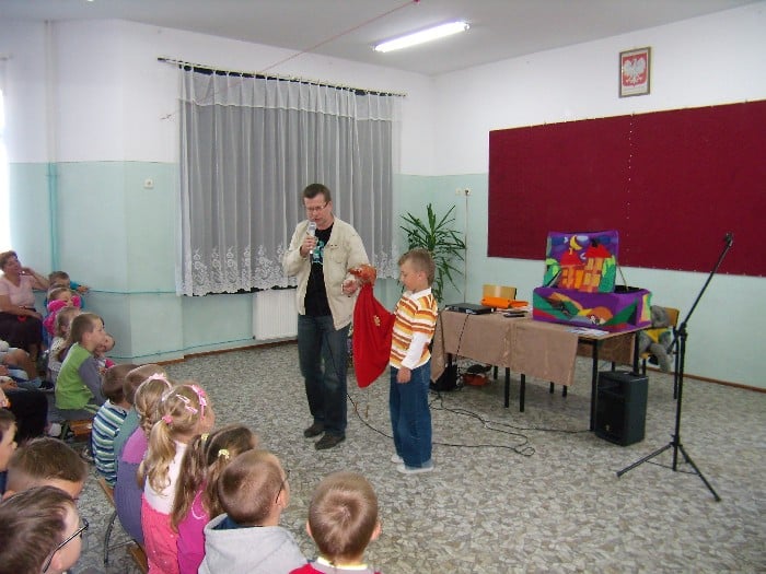 Wnętrze szkoły, grupa dzieci biorąca udział w spotkaniu  z Andrzejem Markiem Grabowskim.