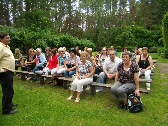 Wnętrze leśniczówki grupa bibliotekarzy z  powiatu działdowskiego siedzi na drewnianych ławkach, świętują Powiatowy Dzień Bibliotekarza.