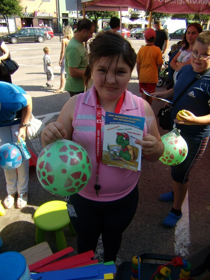 Dziewczynka z zieloną piłką i miesięcznikiem dla dzieci.
