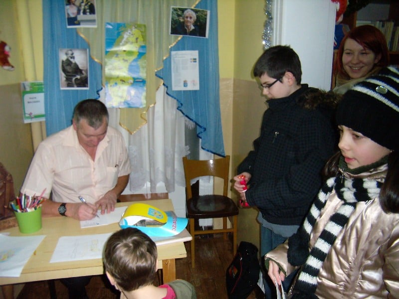 Grupa dzieci podczas ferii w bibliotece na spotkaniu z Marianem Odachowskim, autorem m.in. „Spaceru po Działdowie”. 