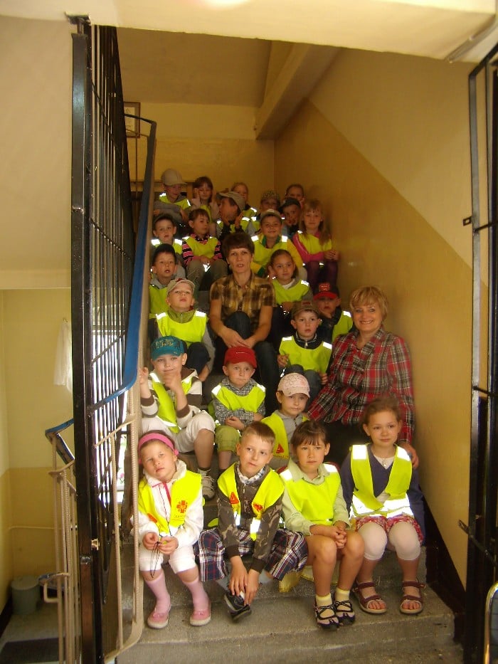 Na schodach siedzi grupa  5-latków z Przedszkola nr 4 w Działdowie z opiekunkami.