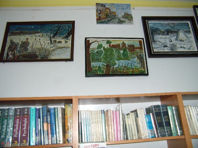W bibliotece na ścianie wisi wystawa obrazów Bernarda Żóralskiego. 