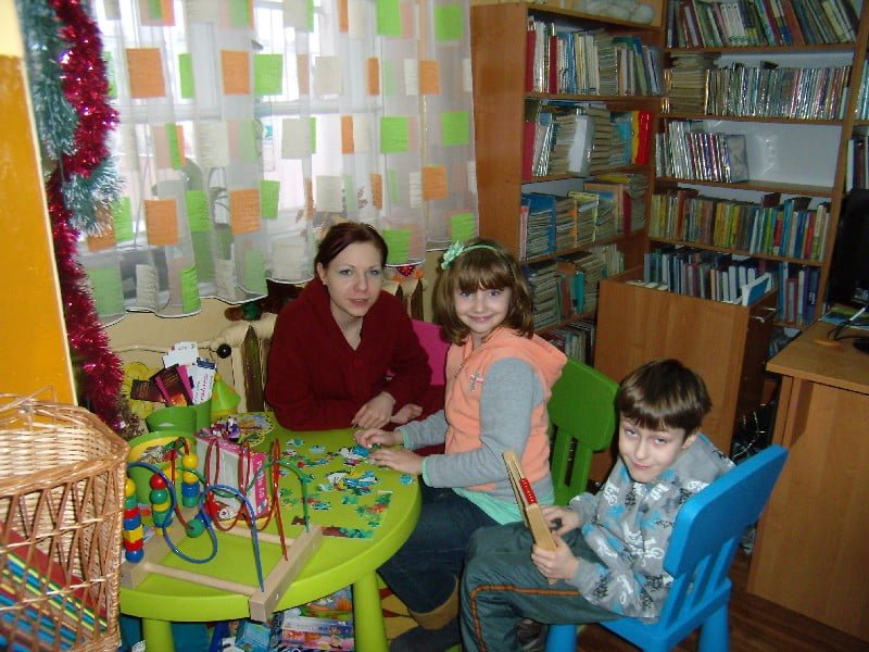 Grupa dzieci podczas ferii na zajęciach w bibliotece układa puzzle.