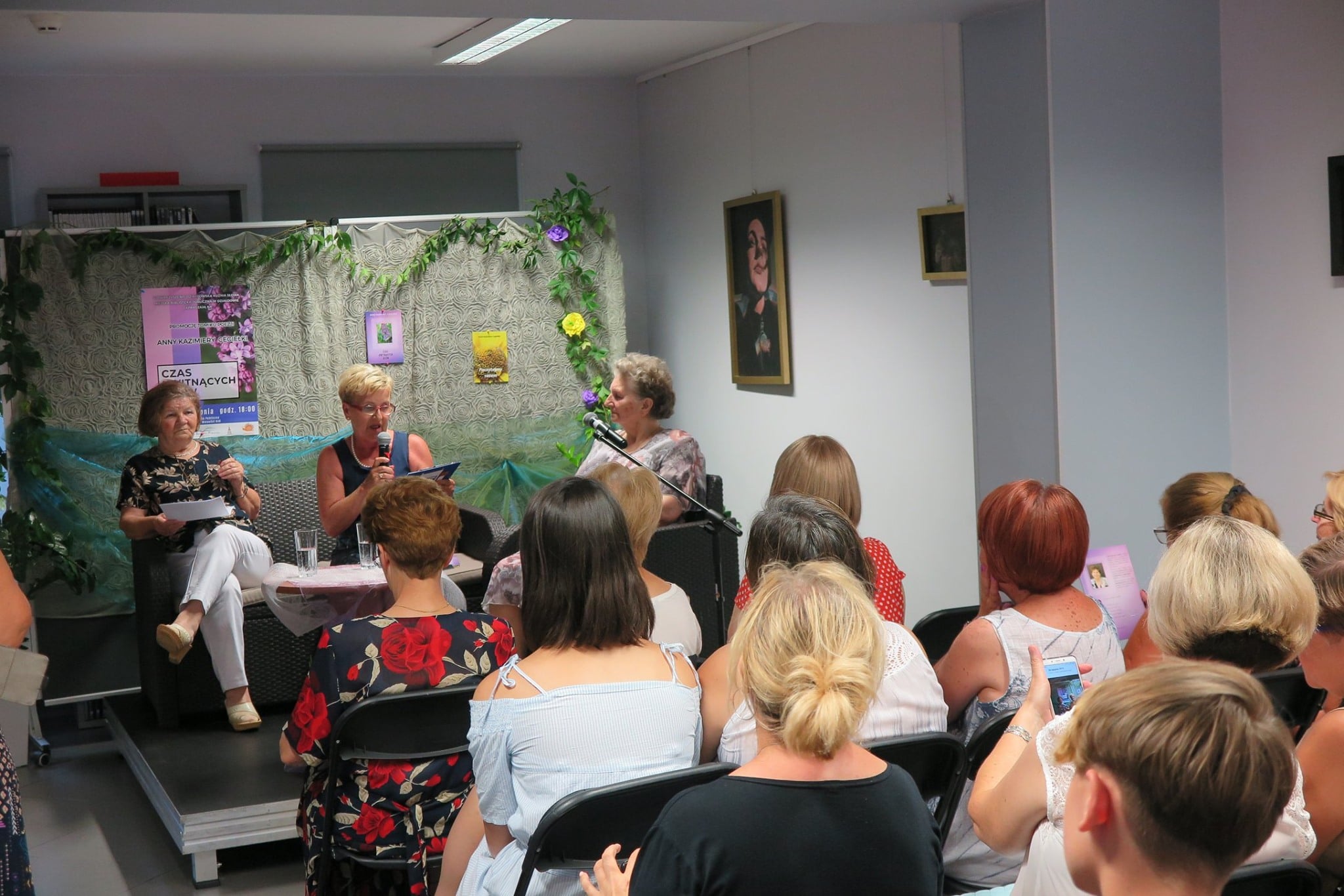 Wnętrze biblioteki, promocja tomiku poezji Anny Kazimiery Cegiełki, na krzesełkach siedzą wszyscy goście.