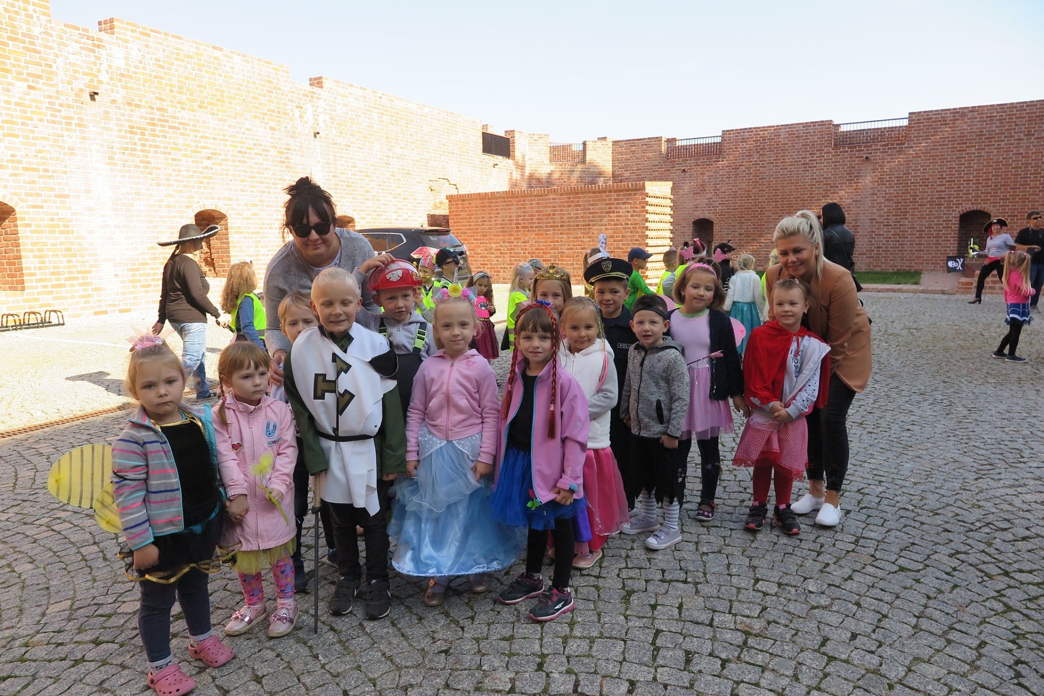 Grupa dzieci z przedszkola wraz z opiekunkami na dziedzińcu zamkowym w Działdowie.