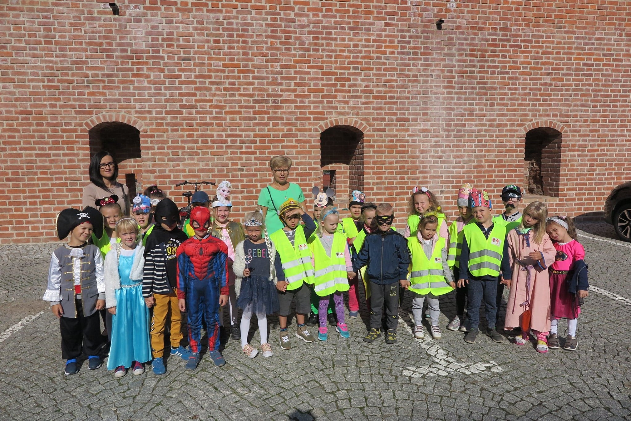 Grupa dzieci z przedszkola wraz z opiekunkami na dziedzińcu zamkowym w Działdowie.