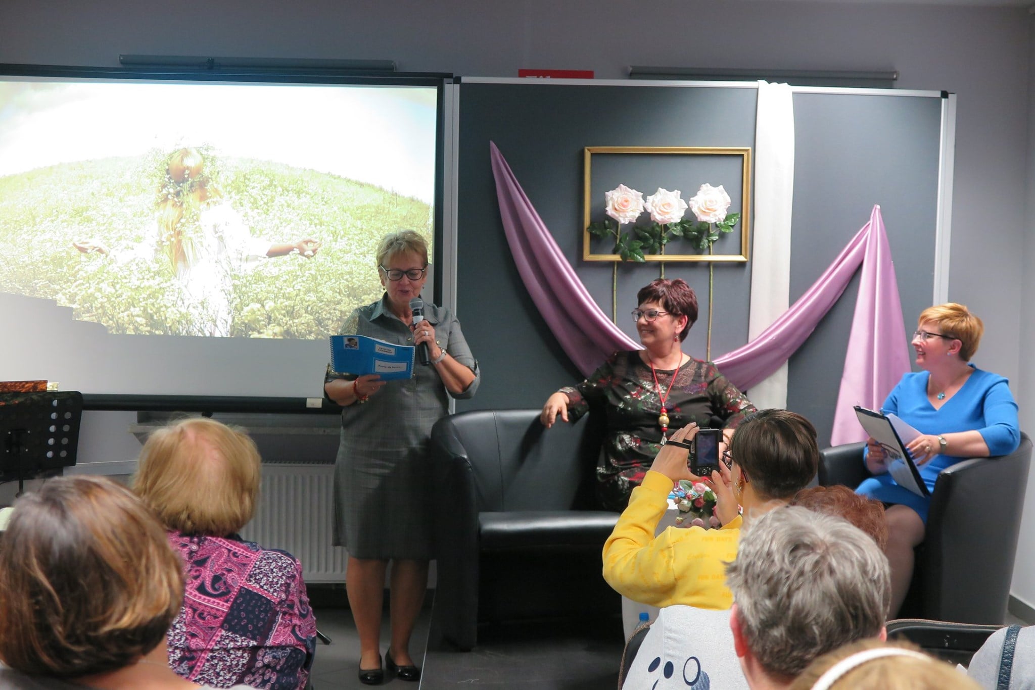 Wnętrze biblioteki, mediateka. Na kanapie poetka Krystyna Sztramska oraz prezes DKS Renata Buczyńska. Recenzję książki wygłosiła Janina Dzenis.