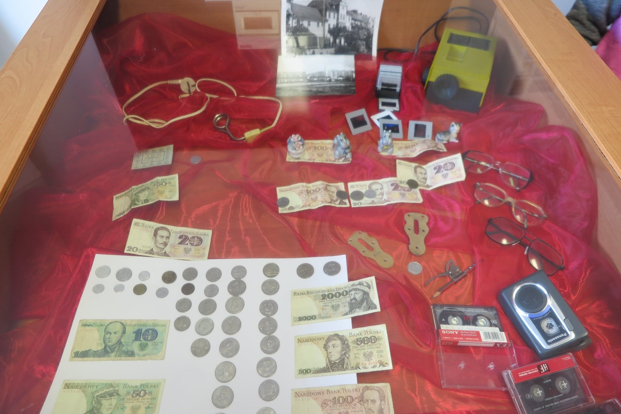 W szklanej gablocie banknoty ,kasety, okulary i inne przedmioty z lat 80.